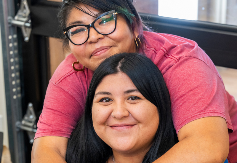 A person standing above a person hugging them