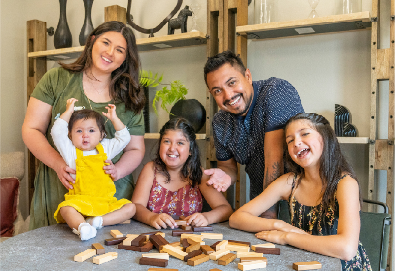 Two parents and three children at a table smiling