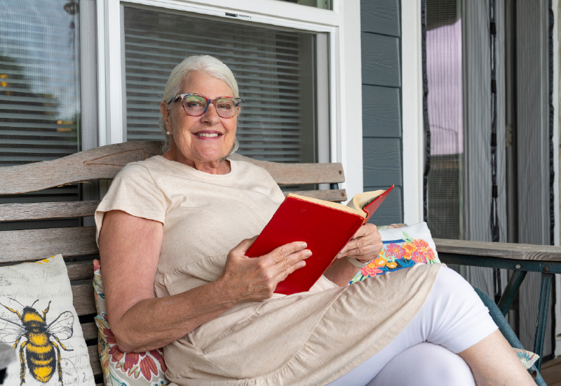 A resident of Deer Run reading a book on a front porch