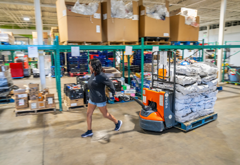 A person using machinery to pull a pallet in a warehouse