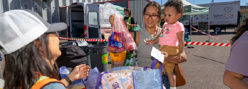 A person holding a bag of apples in a parking lot